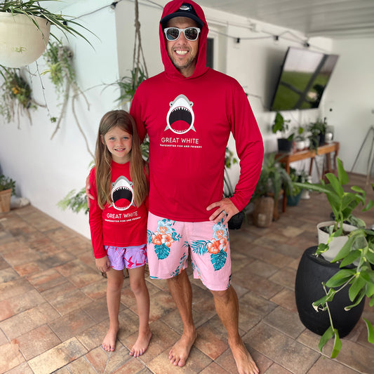 Man and young girl wearing matching Red Great White Shark Upf50 Hooded Sun Protective Shirts by ShapeShifter Fish and Friends in a home setting with plants.