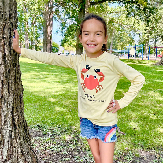 Girl standing by a tree wearing a Yellow Crab Long Sleeve Shirt UPF 50+ sun shirt ShapeShifter Fish and Friends lifestyle