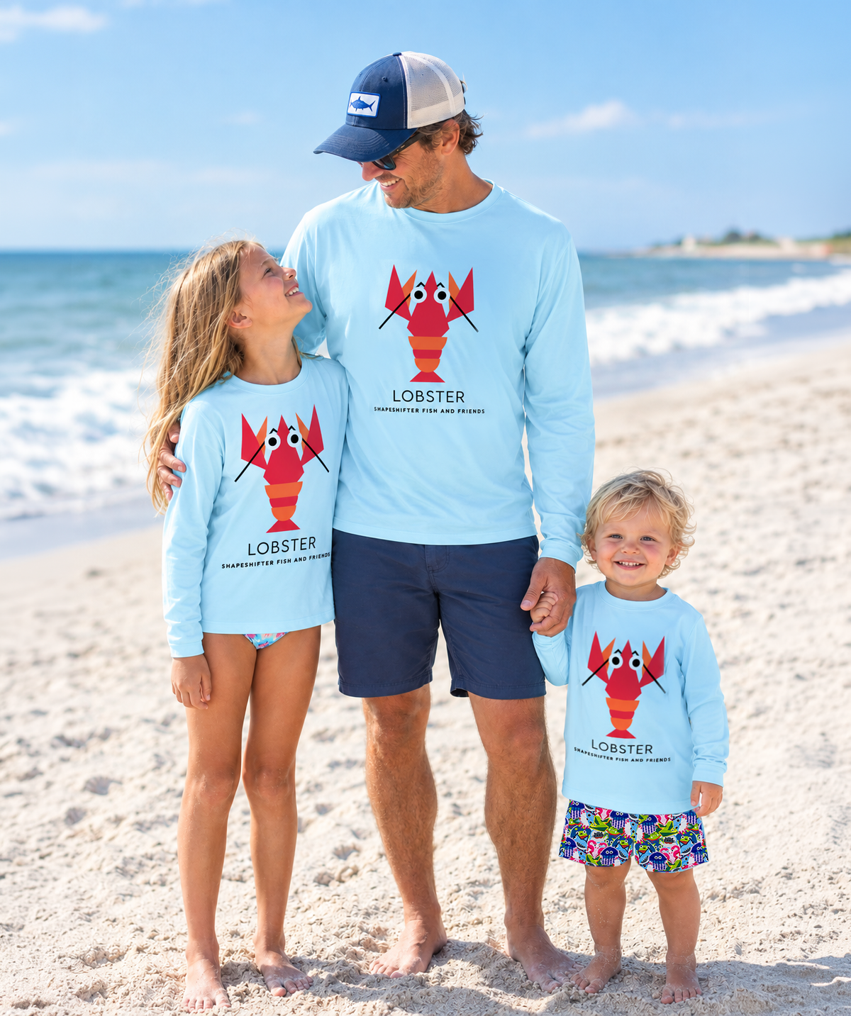 Dad and kids standing on the beach wearing Light Blue Lobster long sleeve UPF 50+ sun protection shirts by ShapeShifter Fish and Friends lifestyle