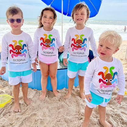 Four children on a beach wearing matching White Rainbow Octopus Sun Protective Shirts by ShapeShifter Fish and Friends lifestyle