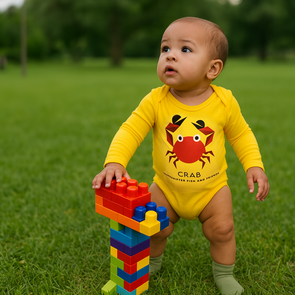 Baby in a Yellow Crab Upf50 Sun Protective Baby Onesie by ShapeShifter Fish and Friends, playing with colorful building blocks on grass.