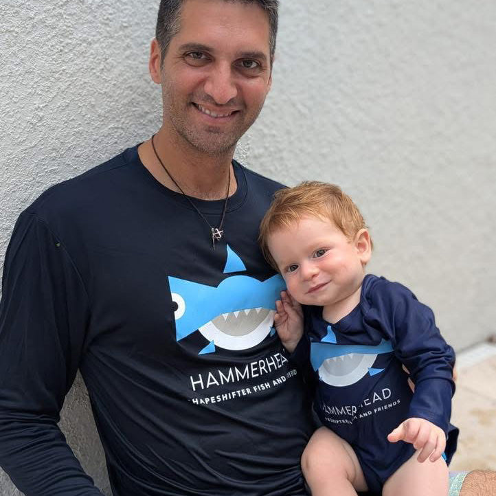 Man and child wearing matching Navy Hammerhead Shark Sun Protective UPF 50+ rashguardsvby ShapeShifter Fish and Friends against a light gray background