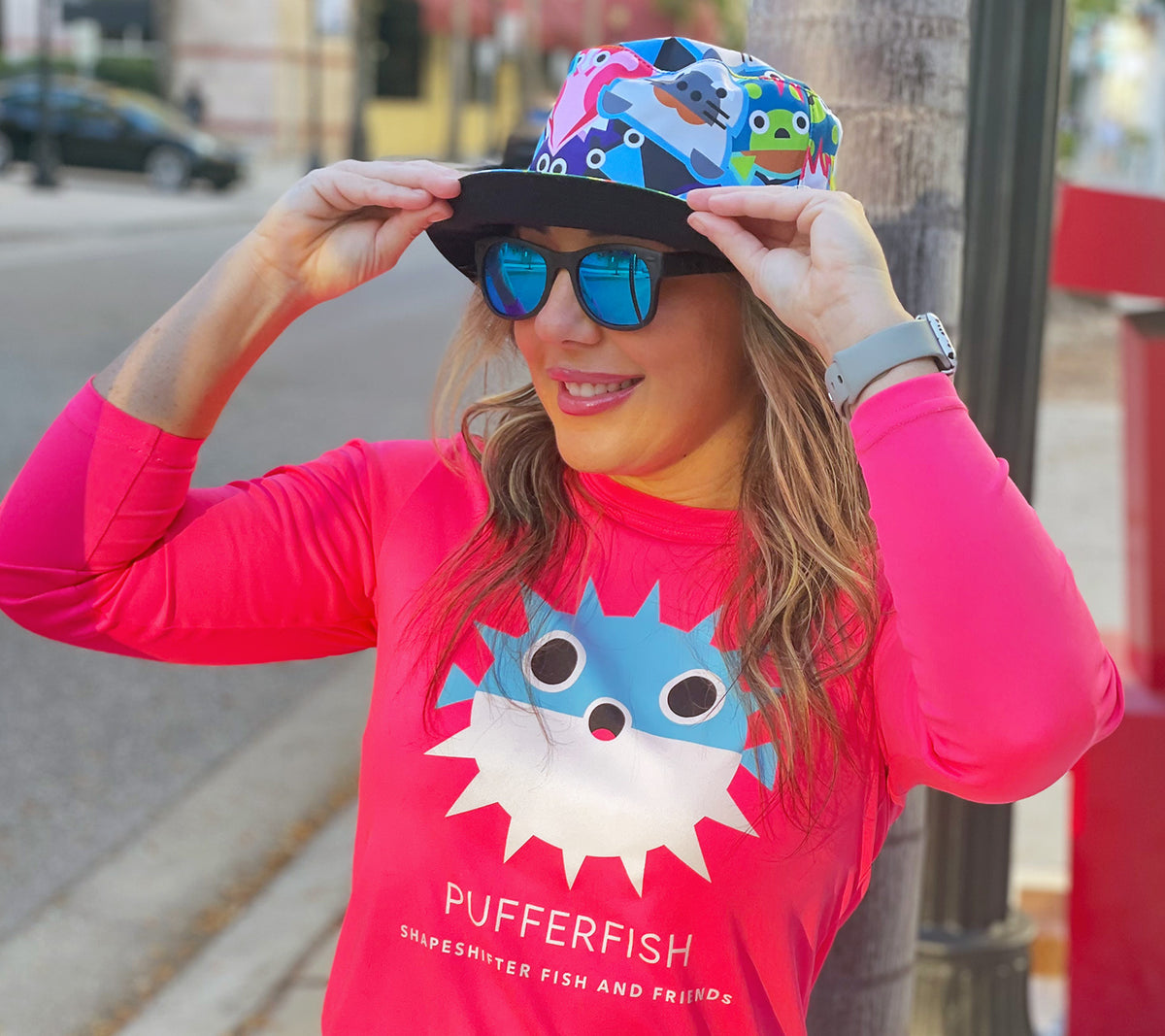 Woman wearing Reversible Fish And Friends Bucket Hat and pink pufferfish sun shirt by ShapeShifter Fish and Friends