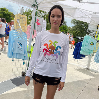Woman wearing a White Rainbow Octopus Sun Protective Long Sleeve Shirt UPF 50+ sunwear by ShapeShifter Fish and Friends at an outdoor market.